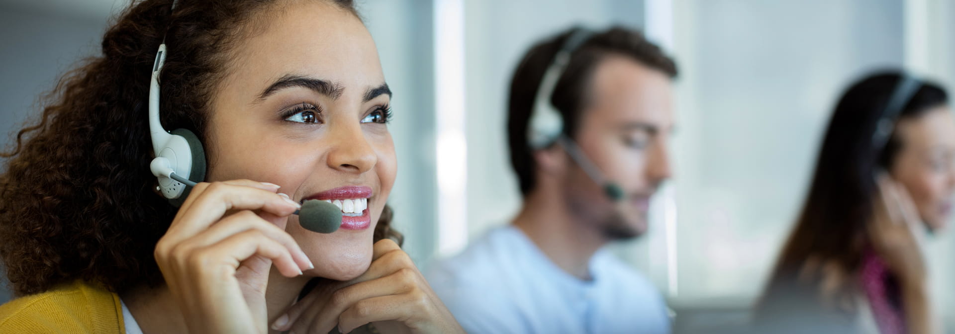 Three people with headsets in a call center